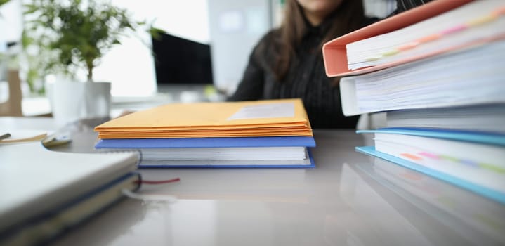 Woman sitting at table with many yellow envelopes and folders closeup. Paper work concept