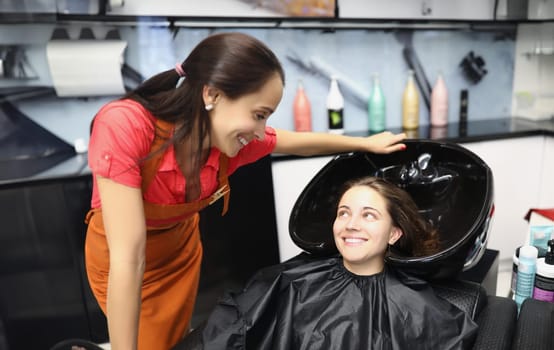 Woman hairdresser communicating with client near hair wash. Hair care concept