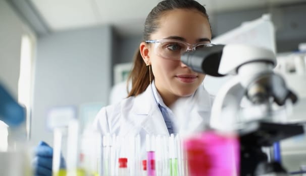 Woman scientist chemist looking through microscope in laboratory. Chemistry lessons at school concept