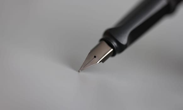 Closeup of metal ink pen head on gray background. Signing of documents concept