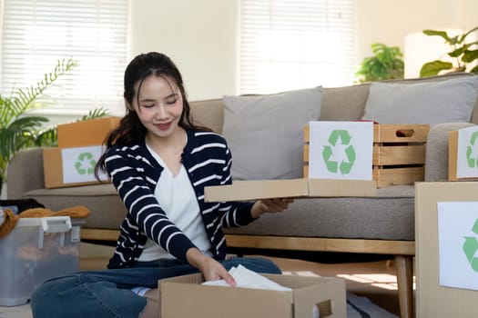 Woman pack box with used clothes for reuse. Reusing, recycling material and reducing waste in fashion, second hand apparel idea. Circular fashion, zero waste concept.