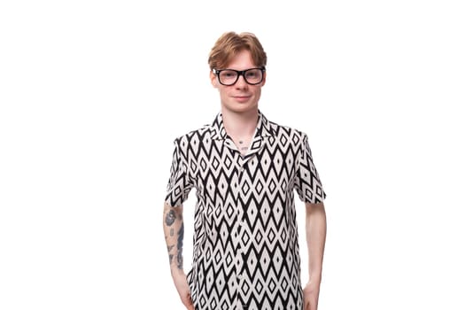 young slender handsome caucasian guy with red hair in glasses and a summer shirt on a white background with copy space.