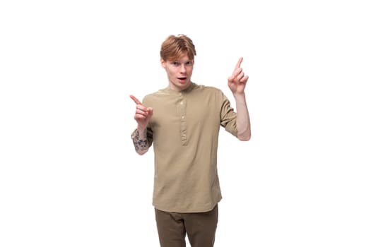 young surprised red-haired man in a beige shirt on a white background.