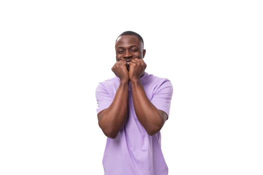 close-up portrait of a young laughing african man in a lilac t-shirt making a grimace.