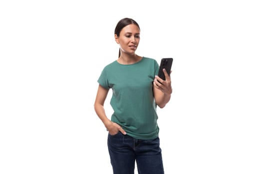 young slender european woman with a ponytail hairstyle dressed in a green t-shirt chatting on a smartphone.