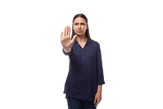 young brunette advertiser woman dressed in a blue blouse with a polka dot pattern shows stop.