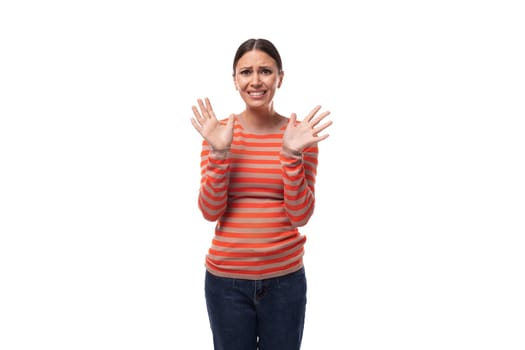 portrait of a young brunette european confused woman dressed in a casual orange sweater.