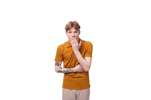 young smart guy with red hair stands thoughtfully on a white background with copy space.