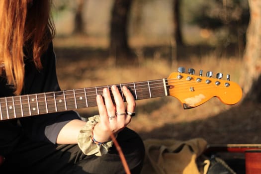 Delve into a harmonious fusion of music and nature as female hands skillfully strum an electric guitar against the backdrop of serene landscapes