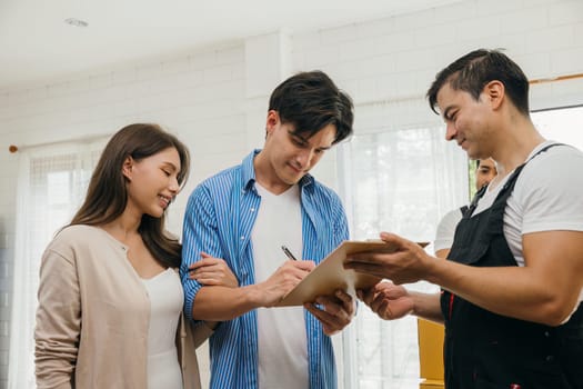 Family examines checklist boxes before signing moving documents. Worker with a box. Professional movers ensure seamless relocation service. Teamwork and efficient home moving portrayed. Movind Day