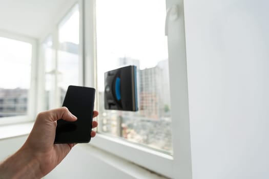 Modern window washer robot performs work on a dirty window. Cleaning the house with smart devices. Automatic window cleaning robot, housekeeper. High quality photo
