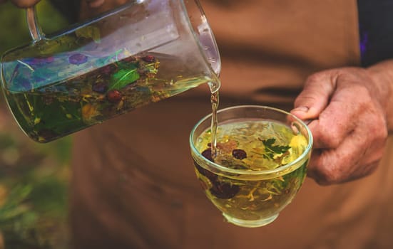 An elderly woman brews herbal tea. Selective focus. Drink.