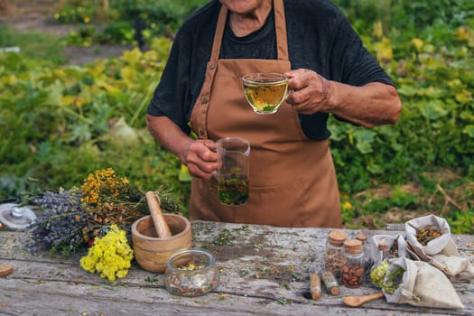 An elderly woman brews herbal tea. Selective focus. Drink.