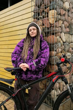 Lifestyle concept. Young woman with informal dreadlocks hairstyle rented a bicycle.