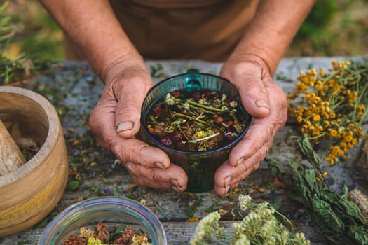 An elderly woman brews herbal tea. Selective focus. Drink.