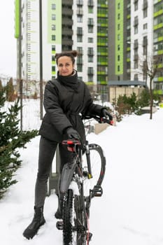 Lifestyle concept, young brunette woman in a black winter jacket rides a rented bicycle.