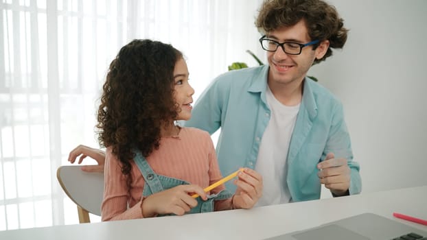 Caucasian father put pencil on ear while cute daughter looking at dad and put pencil on ear. Attractive parent looking at screen while explain programing system or coding engineering prompt. Pedagogy.