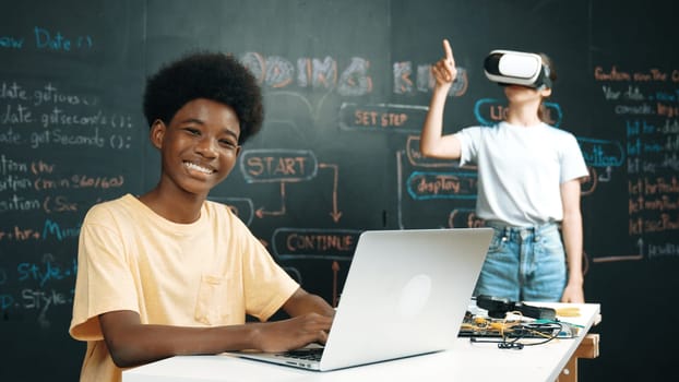 Smart african student programing and coding innovative system while caucasian girl enter in metaverse or virtual world by using VR or head set at blackboard in STEM technology classroom. Edification.