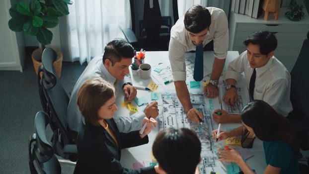 Group of diverse team planning strategy while sitting at table with project plan. Top aerial view of smart business people working together to brainstorm and design house construction. Alimentation.