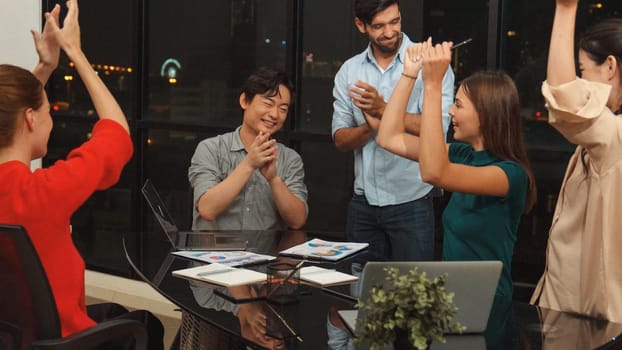 Businesspeople putting hands together and clapping hands to celebrate successful project at modern office with night city view. Group of manager with stacks of hands. Teamwork, trust. Tracery