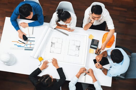 Top view banner of diverse group of civil engineer and client working together on architectural project, reviewing construction plan and building blueprint at meeting table. Prudent