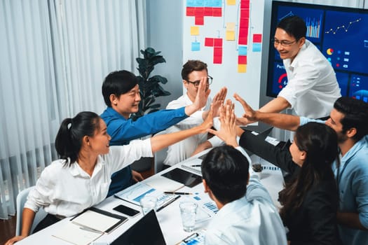 Analyst team leader celebrate and high five together with his colleague after successful data analysis meeting using FIntech software power with business intelligence or BI dashboard. Prudent