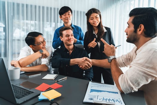 Diverse group of office employee worker shake hand after making agreement on strategic business marketing meeting. Teamwork and positive attitude create productive and supportive workplace. Prudent