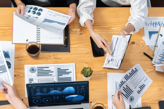 Top view diverse group of business analyst team analyzing financial data report paper on meeting table. Chart and graph dashboard by business intelligence analysis. Meticulous