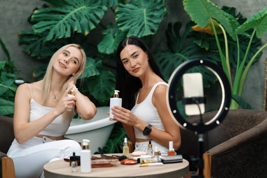 Two beautiful content creator making natural beauty and cosmetic tutorial on green plant garden video. Beauty blogger showing how to beauty care to social medial audience using selfie stick . Blithe