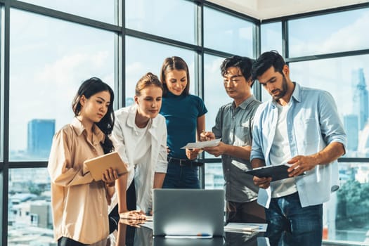 Asian project manager uses laptop displayed data analysis while professional business team brainstorming marketing idea at business meeting. Working together,sharing idea, planing strategy. Tracery.