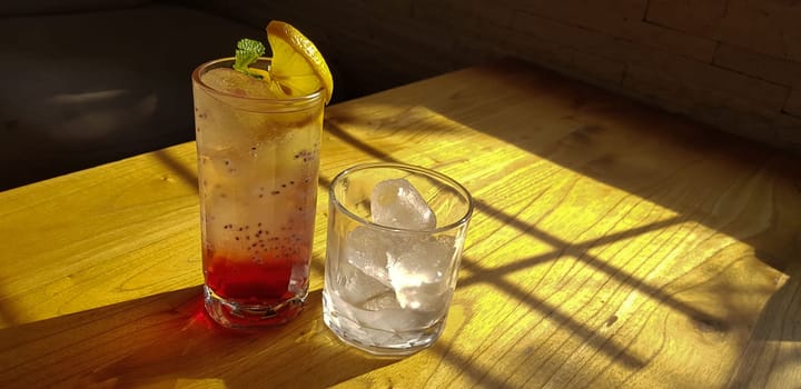 Transparent Glasses with sweet drinks inside with colorful drink, with shadow and table background with ice cubes on a bar restaurant