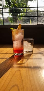 Transparent Glasses with sweet drinks inside with colorful drink, with shadow and table background with ice cubes on a bar restaurant