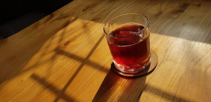 Transparent Glasses with sweet drinks inside with colorful drink, with shadow and table background with ice cubes on a bar restaurant