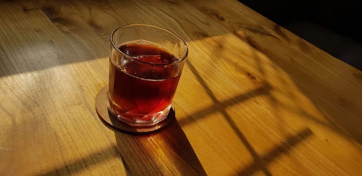 Transparent Glasses with sweet drinks inside with colorful drink, with shadow and table background with ice cubes on a bar restaurant