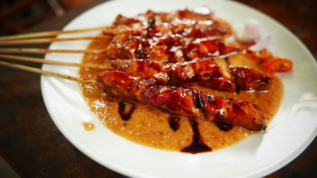 Chicken satay or Indonesian sate ayam, grilled chicken satay with peanut and soy sauce completed with chili and onion, indonesian delicacy