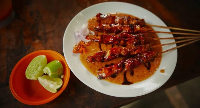 Chicken satay or Indonesian sate ayam, grilled chicken satay with peanut and soy sauce completed with chili and onion, indonesian delicacy
