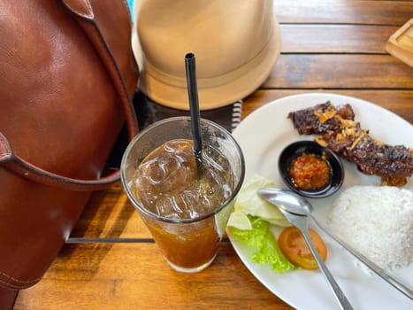 Spicy hot grilled honey roasted spare ribs from summer BBQ served with hot chili paste and rice also ice tea served in white plate