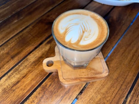 beautiful cup of cappuccino coffee with latte art in the wooden space background