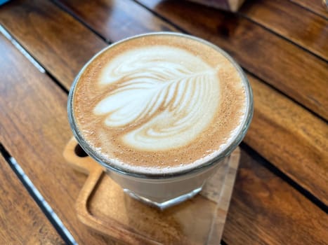 beautiful cup of cappuccino coffee with latte art in the wooden space background