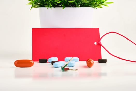 A red card on a white background. There are pills nearby. A place to copy. Concept photo