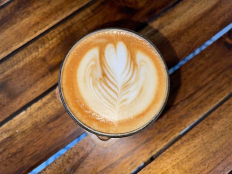 beautiful cup of cappuccino coffee with latte art in the wooden space background