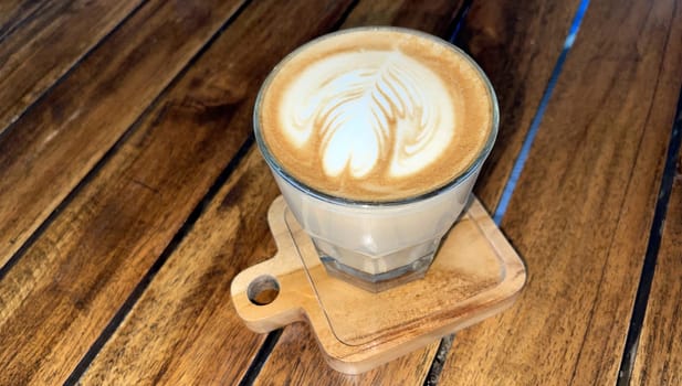 beautiful cup of cappuccino coffee with latte art in the wooden space background