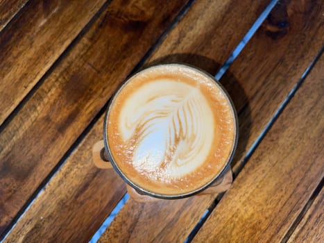 beautiful cup of cappuccino coffee with latte art in the wooden space background