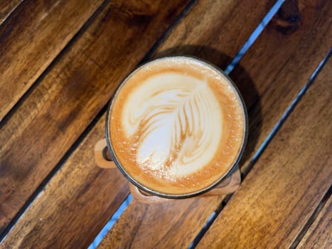 beautiful cup of cappuccino coffee with latte art in the wooden space background