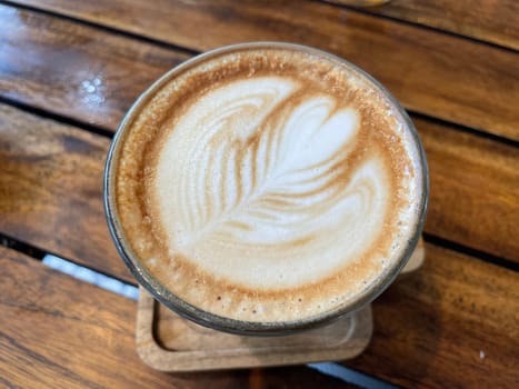 beautiful cup of cappuccino coffee with latte art in the wooden space background