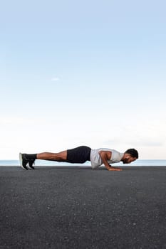 Side view of young African American male wearing sportswear doing push ups outdoors. Copy space. Vertical. Active and healthy lifestyle concept.