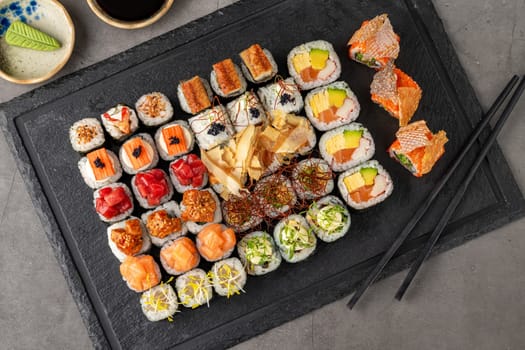 Sushi set of various products on a black stone plate