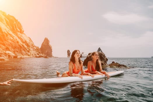 Woman sup yoga. Middle age sporty woman practising yoga pilates on paddle sup surfboard. Female stretching doing workout on sea water. Modern individual hipster outdoor summer sport activity