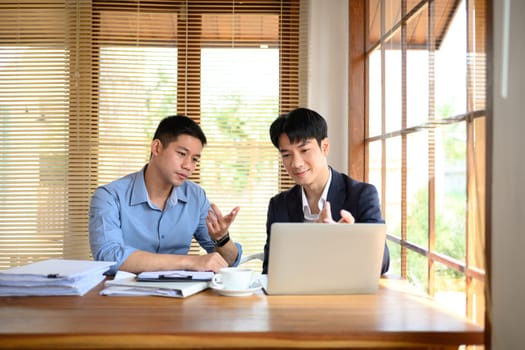 Portrait of smart businessmen discussing financial market data on laptop in their office.