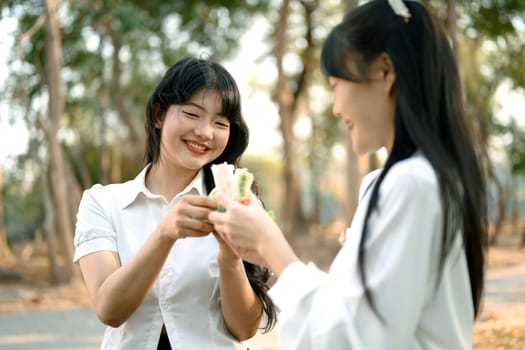 Cheerful young woman enjoying sandwich with her colleague during lunch break at outdoor.